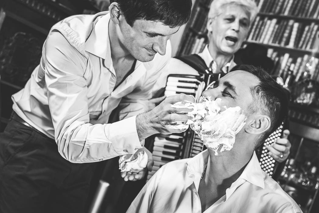 Fotograf nunta Bucuresti surprinde momentul cand cavalerul de onoare barbiereste mirele.