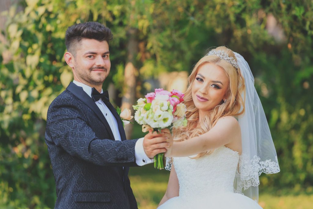 Fotograf nunta Bucuresti, mire si mireasa in parc tinand amandoi buchetul miresei