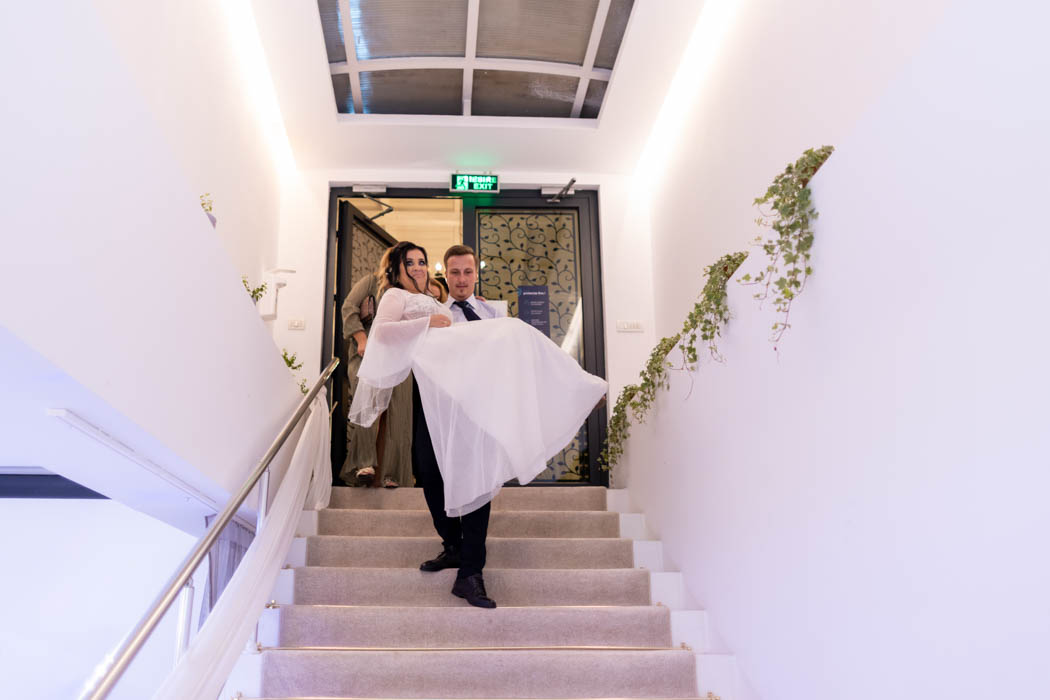 Instantaneu surprins de fotograf nunta Bucuresti: mireasa este furata, pe scari, de cavalerul de onoare al mirelui.