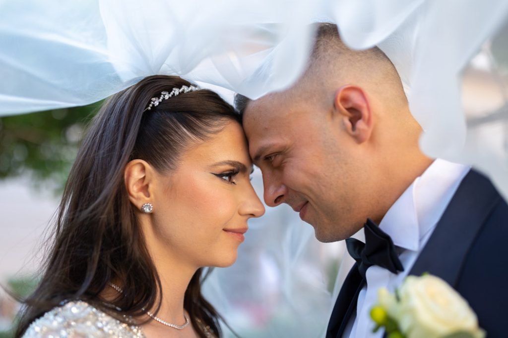 Mire si mireasa cu fruntile lipite sub voal,instantaneu surprins de fotograf nunta in Bucuresti