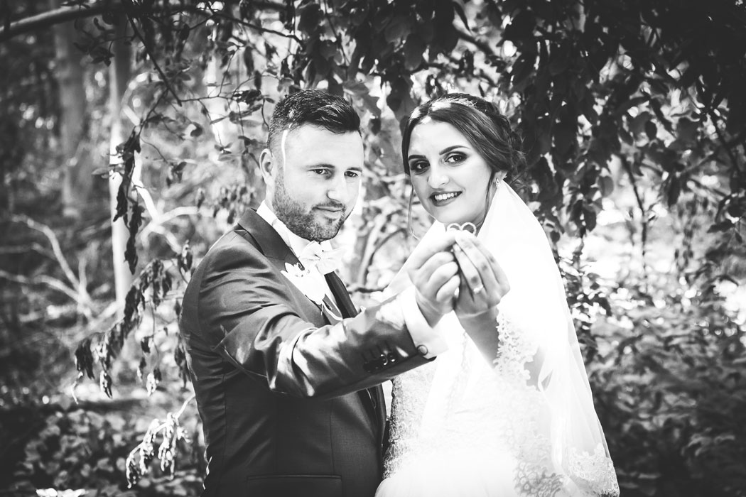 mirele si mireasa cu verighetele spre fotograf, portret de nunta monocrom alb-negru,