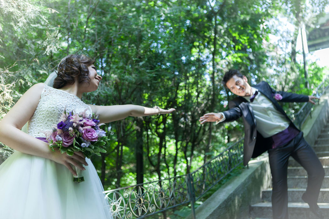 Mireasa intinde mana pentru a prinde mirele aflat mai sus pe scari, cadru surprins de fotograf la sedinta foto de nunta