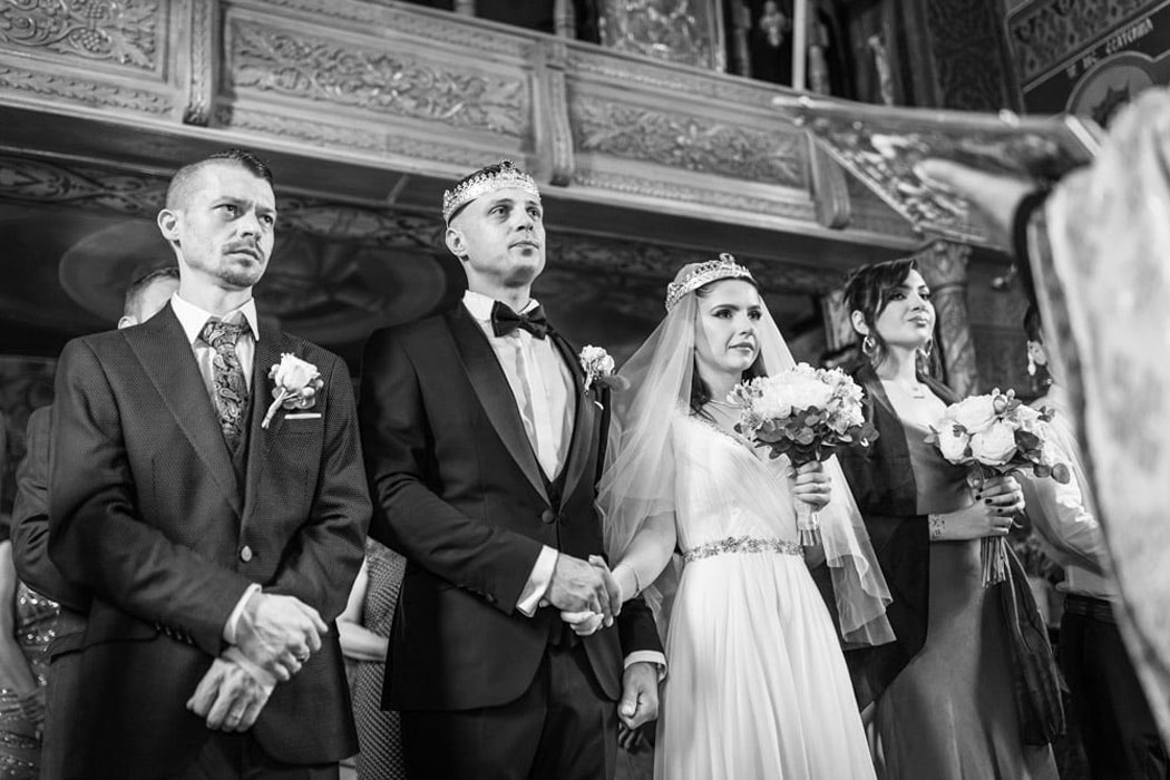 Mirii cu nasii in fata preotului, la inceputul slujbei de nunta